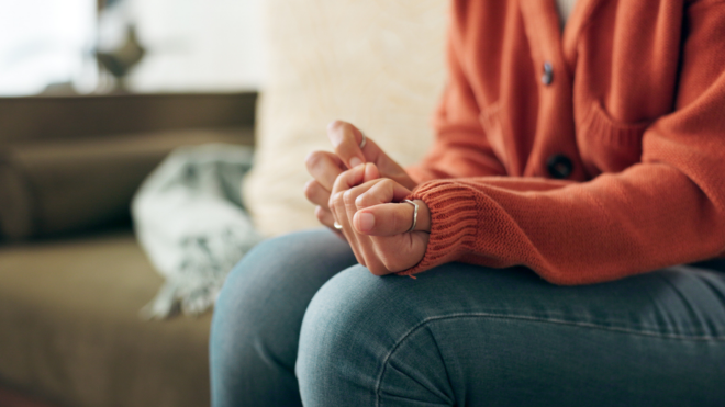 woman's torso sitting on bench clutching her hands