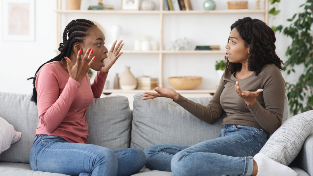 two Black women sitting on a couch arguing