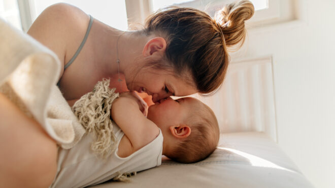 Mom and baby boy cuddling on the bed in the morning