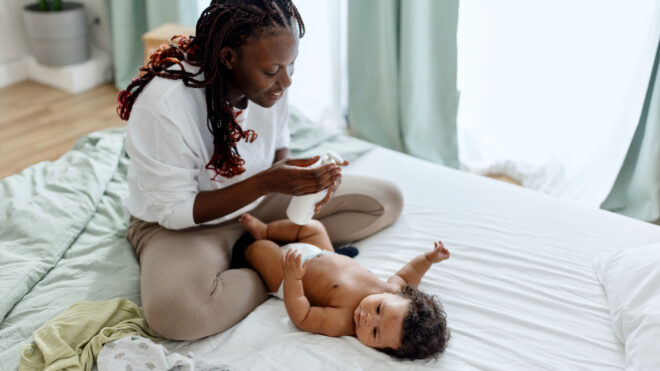 Mother putting dy lotion on her baby boy