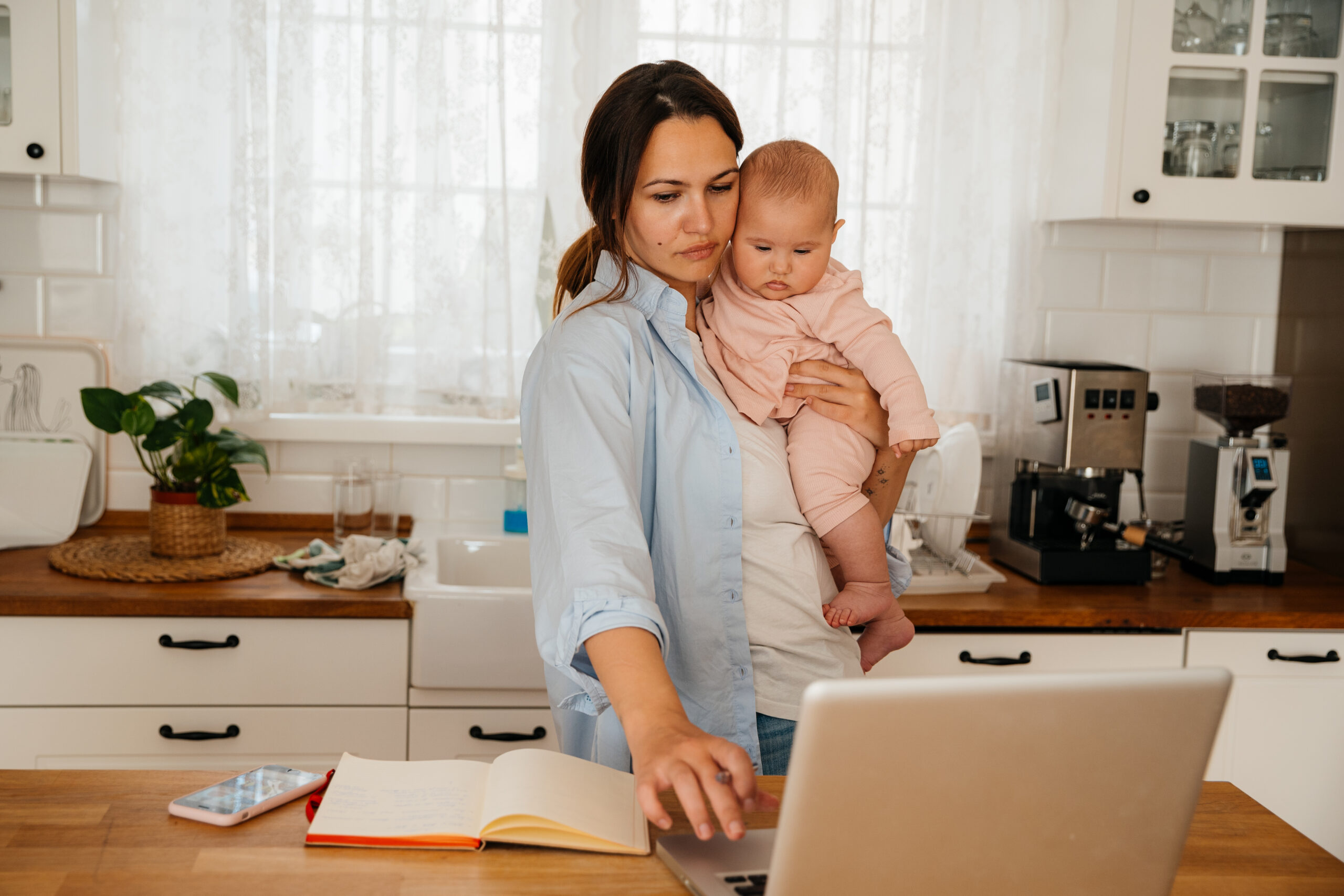 Mother talking on a phone and working from home while taking care of her new born baby girl