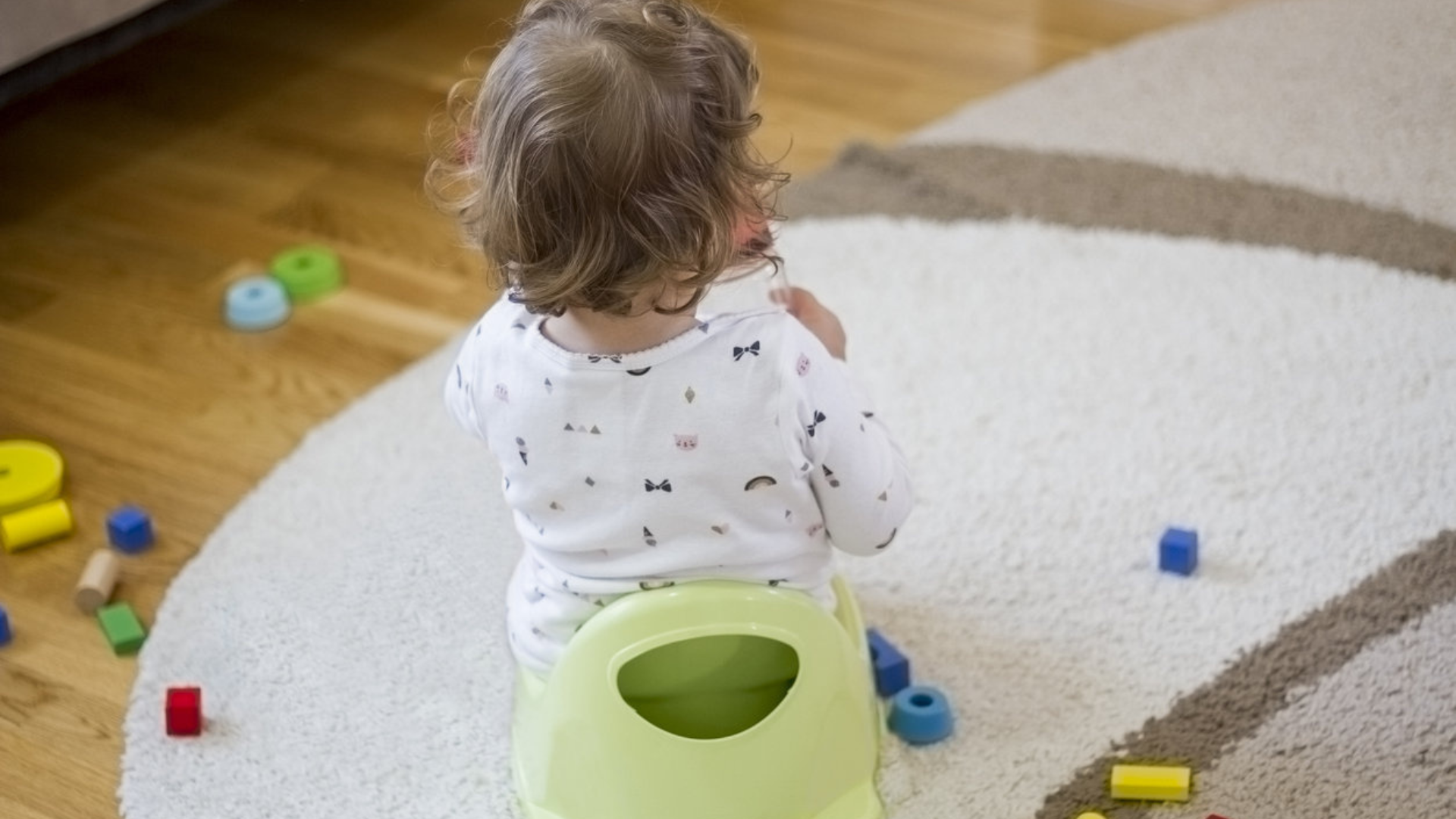 back of toddler's head while sitting on plastic potty
