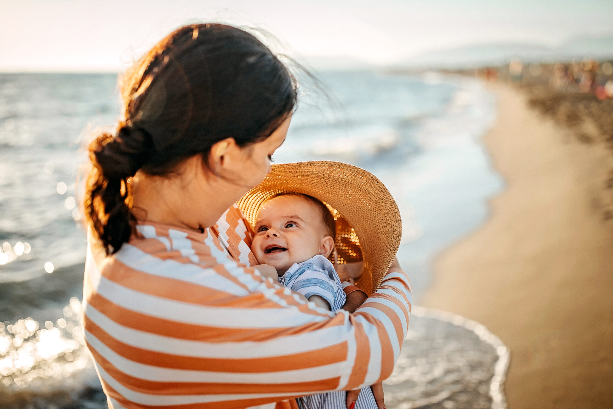 Mother holding baby near the sea, summer baby registry
