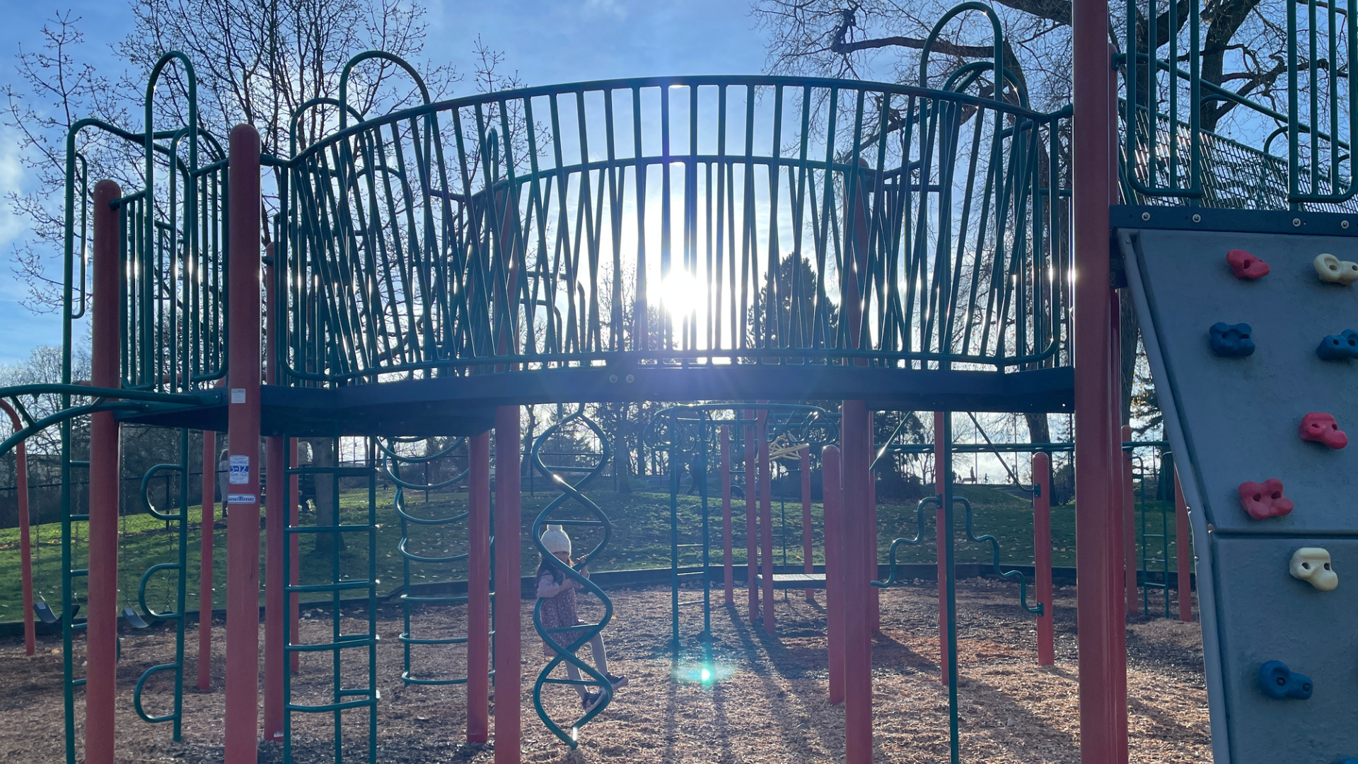 a bright sun shining behind empty playground equipment