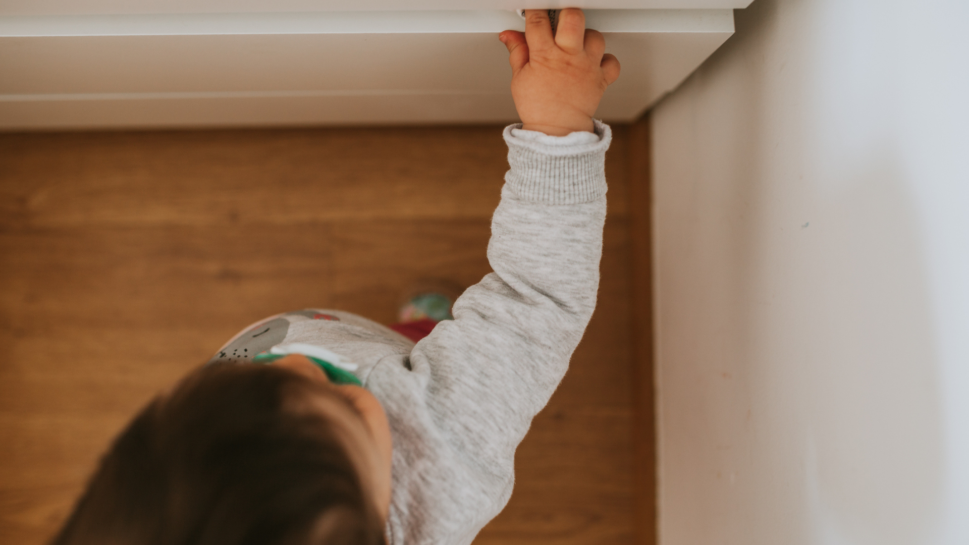 toddler reaching to open drawer