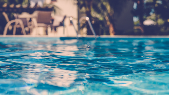 blurred swimming pool surface with chairs in the background