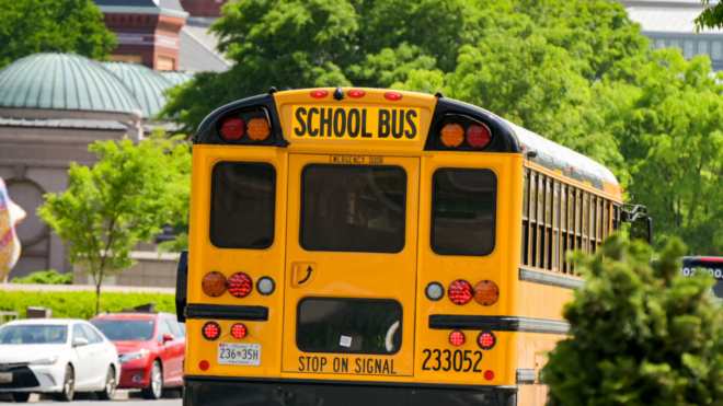 back of yellow school bus as it drives down a city street