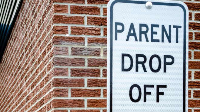 School Zone Parent Drop Off Sign next to a brown brick exterior wall