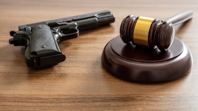Crime, gun carry and use punishment concept. Judge gavel and handgun on table, close up