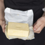 A hand holds butter in a pack close-up. Process of making sandwiches with butter.