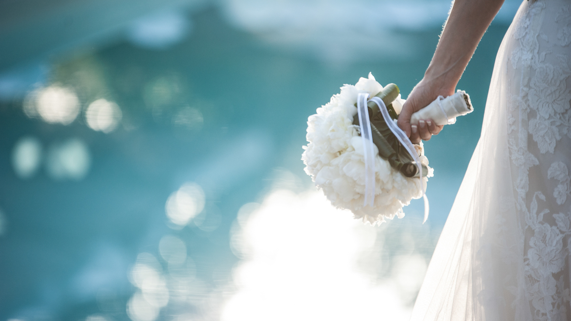 bride standing near a pool holding her bouquet