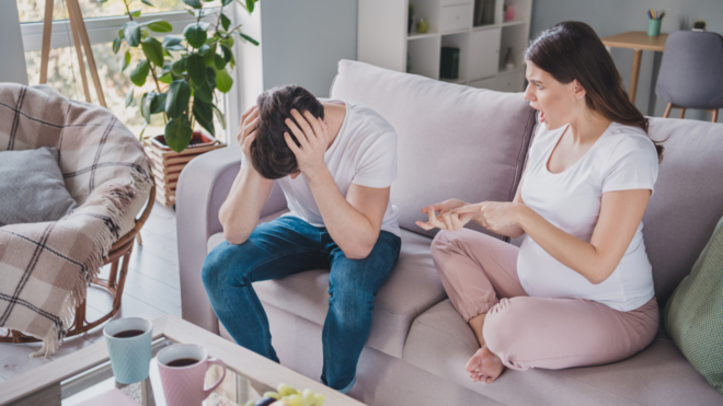man with his head in his hands while arguing with his pregnant wife