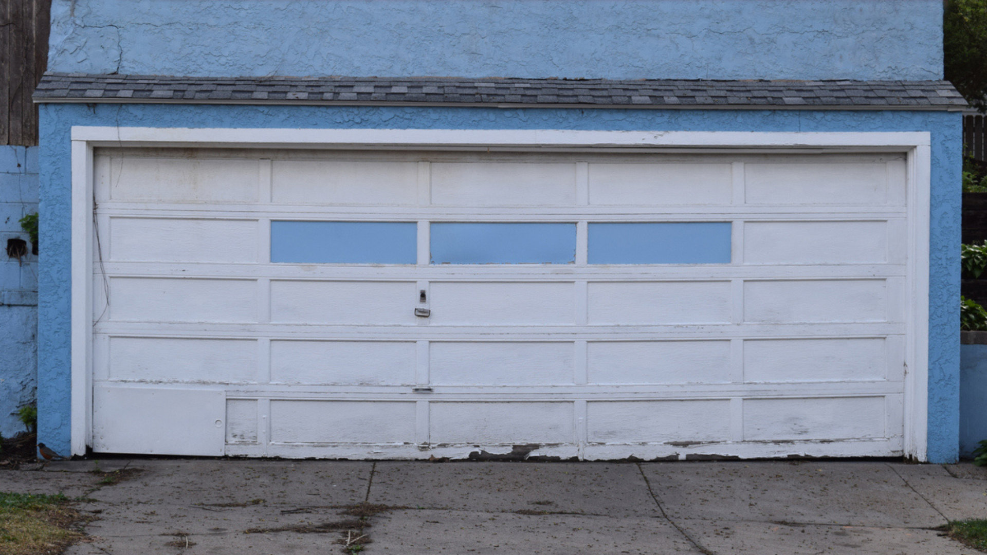 a blue and white garage door with peeling paint