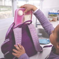 Girl packing lunch box for school / kindergarten.