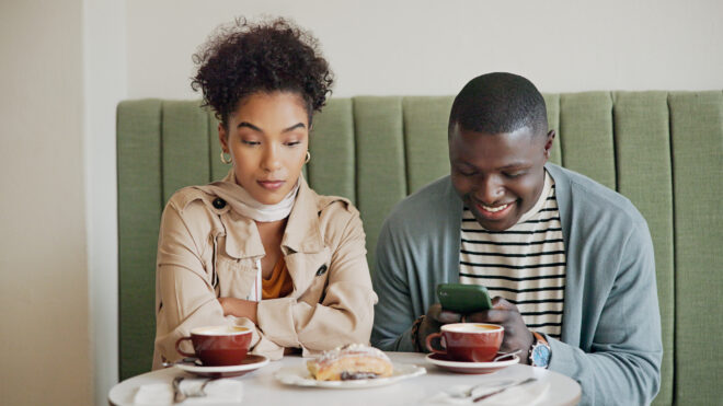 Man and woman at a restaurant, man is ignoring the woman
