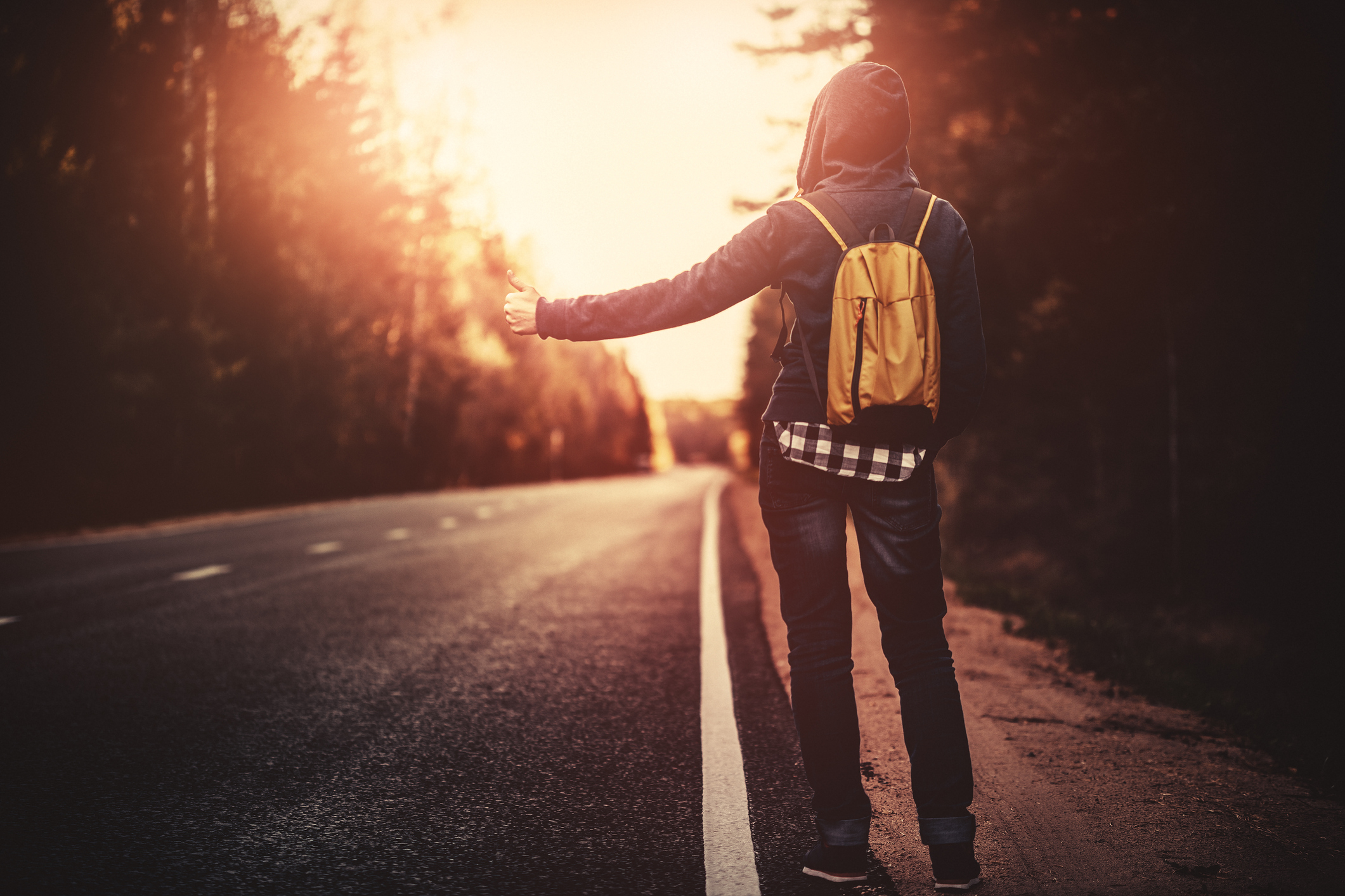 Hitchhiking traveler trying to stop the car on road Hitchhiking traveler with backpack