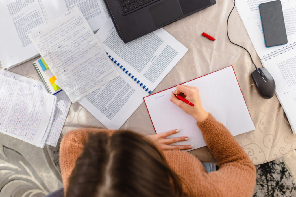 A young woman sitting at a desk in her home, earnestly studying for an upcoming exam.