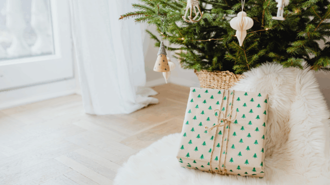 Present under the tree has white wrapping paper with green trees