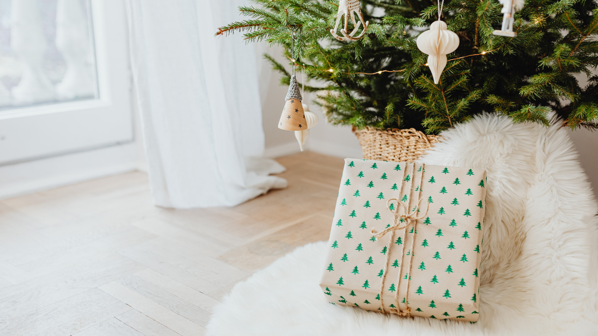 Present under the tree has white wrapping paper with green trees