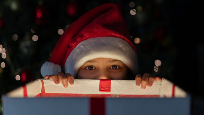 Mischievous girl getting a sneak peek of her Christmas present
