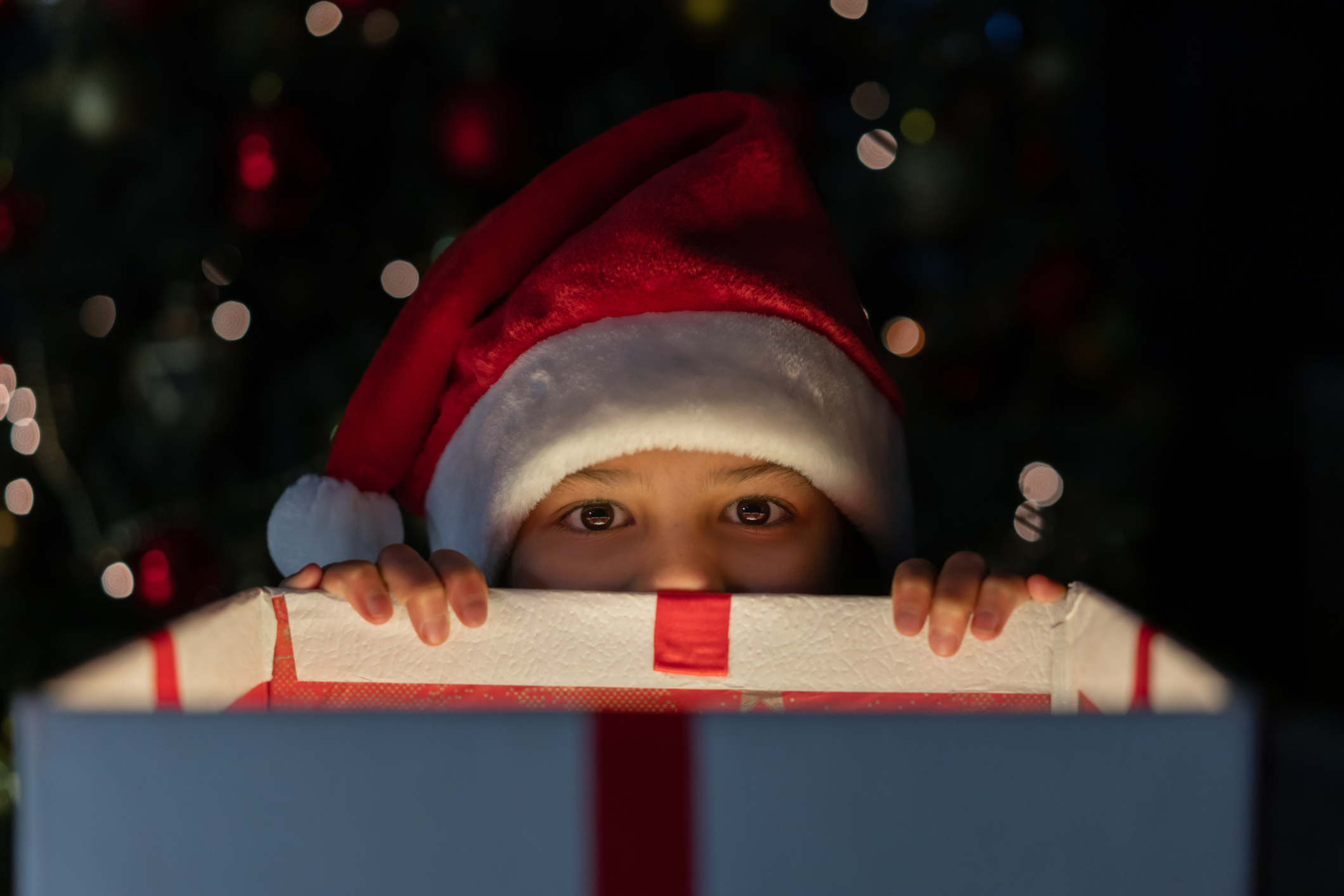 Mischievous girl getting a sneak peek of her Christmas present