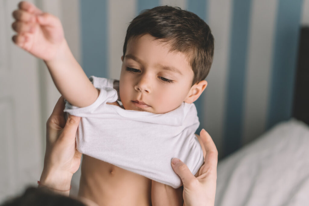mom putting shirt on son