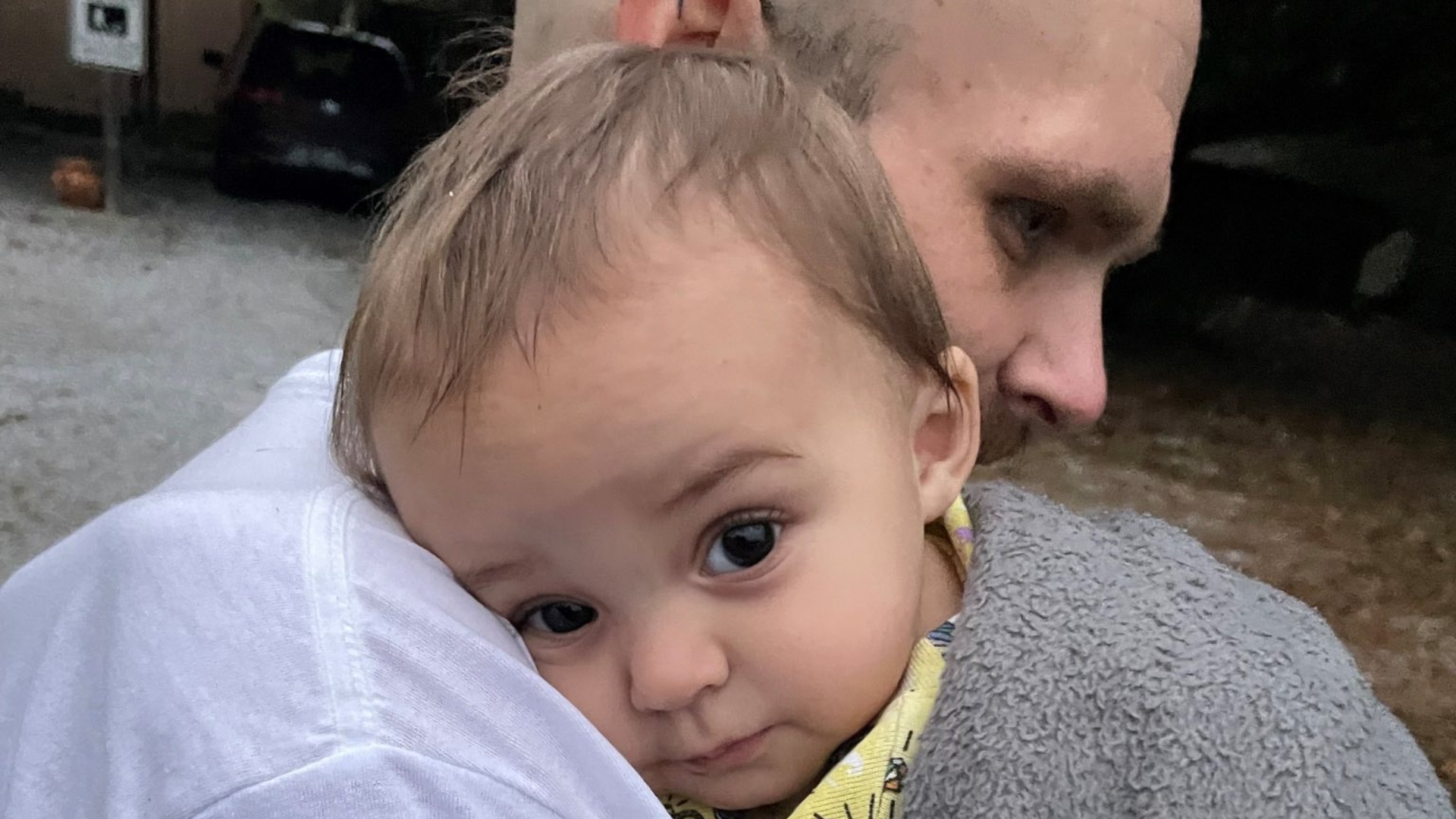 young girl o her father's shoulder looking at camera