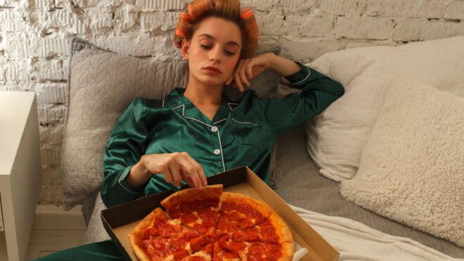 young fashion boring woman in pajama with pizza box in bed at home, quarantine leisure