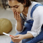 Worried woman holding pregnancy test. stock photo