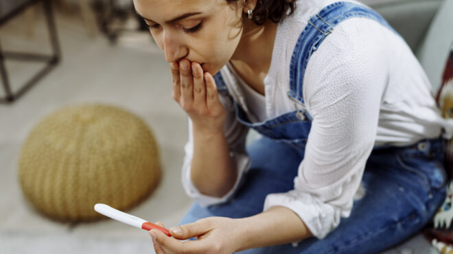 Worried woman holding pregnancy test. stock photo. Shallow DOF. Developed from RAW; retouched with special care and attention; Small amount of grain added for best final impression. 16 bit Adobe RGB color profile.