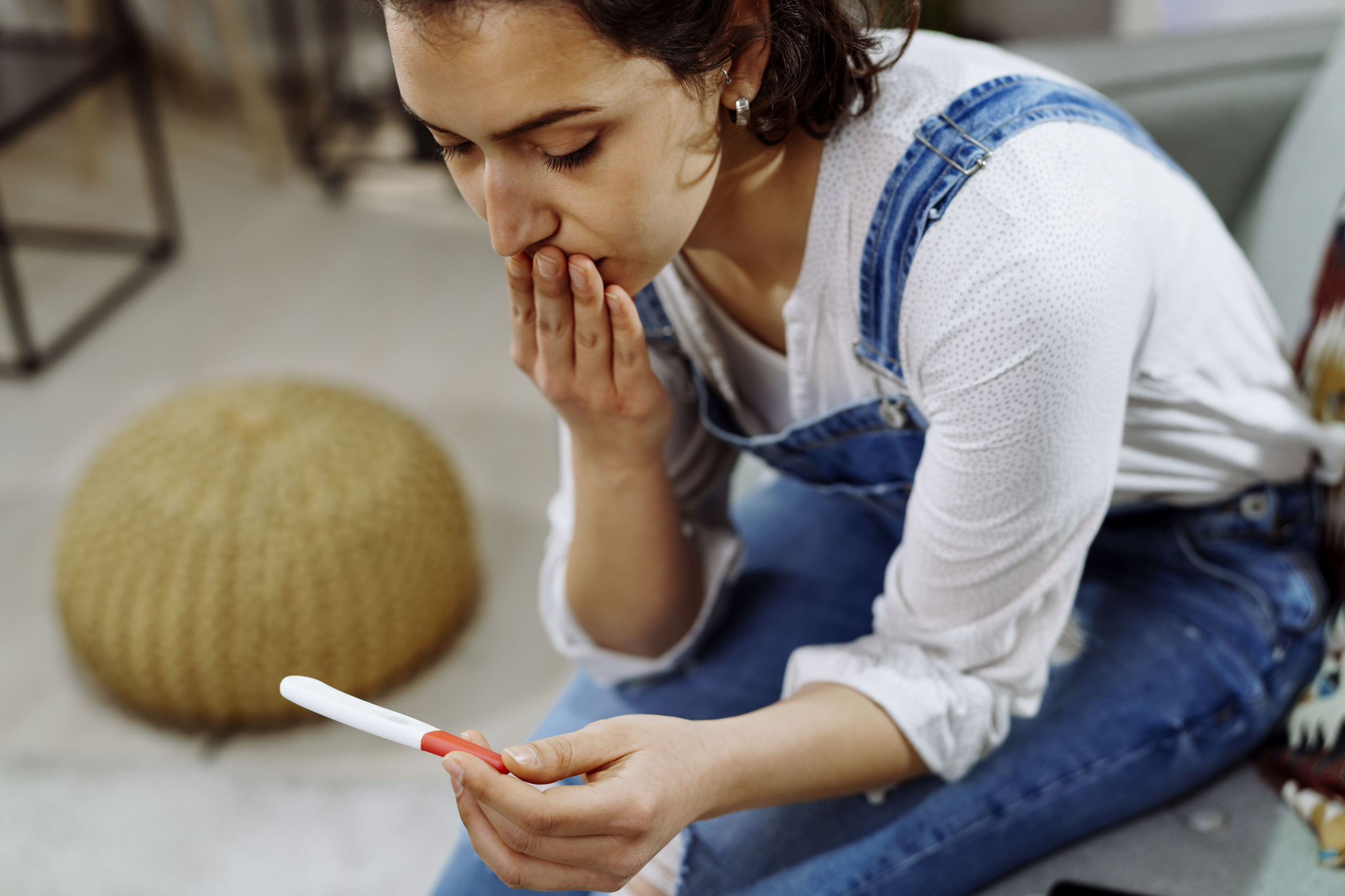 Worried woman holding pregnancy test. stock photo. Shallow DOF. Developed from RAW; retouched with special care and attention; Small amount of grain added for best final impression. 16 bit Adobe RGB color profile.