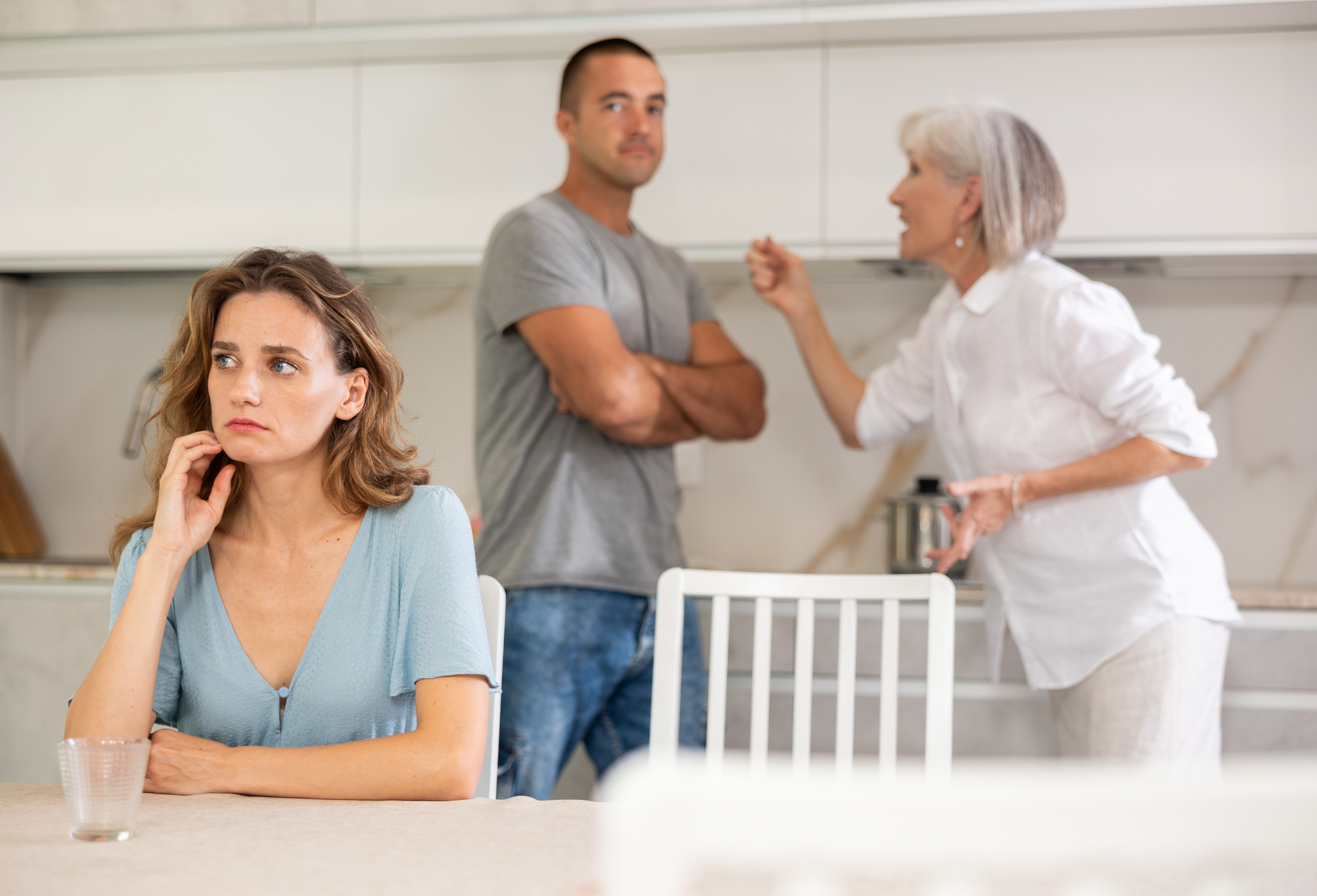 Elderly woman during family quarrel with married couple in kitchen