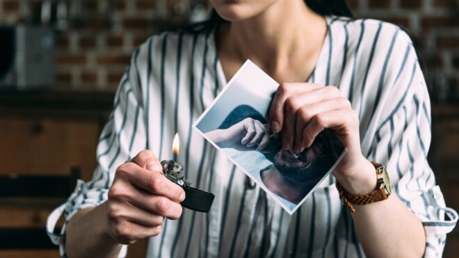 cropped shot of young woman burning photo card of ex-boyfriend