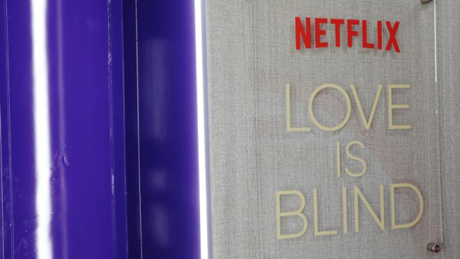 A promo shot from Getty images showing the Netflix Love Is Blind title on a gray background at an event