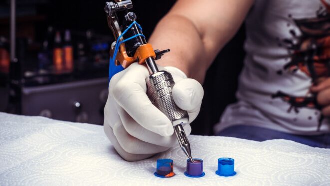 A tattoo artist choosing between three ink pots on a paper towel