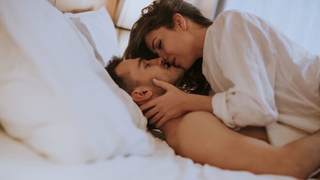 Beautiful young loving couple lying on bed in the room