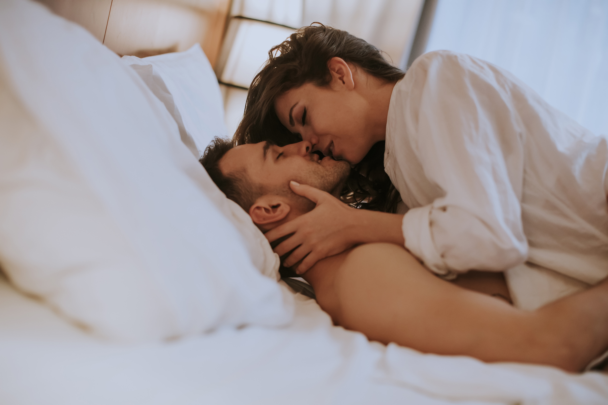Beautiful young loving couple lying on bed in the room