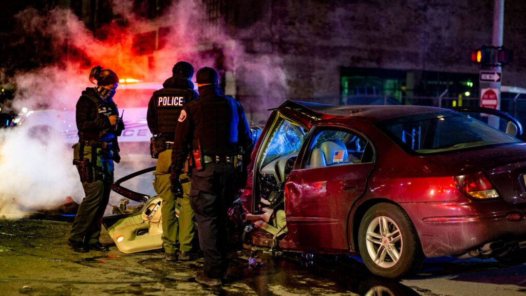 A vehicle crash involving a red car in the nightime hours with multiple police on the scene