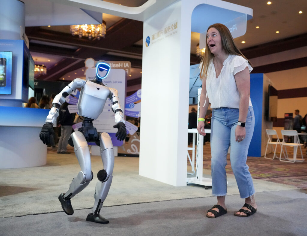 Kelly Ritz of Walnut Creek, California, reacts while dancing with a Unitree G1 humanoid robot at the SXSW Expo