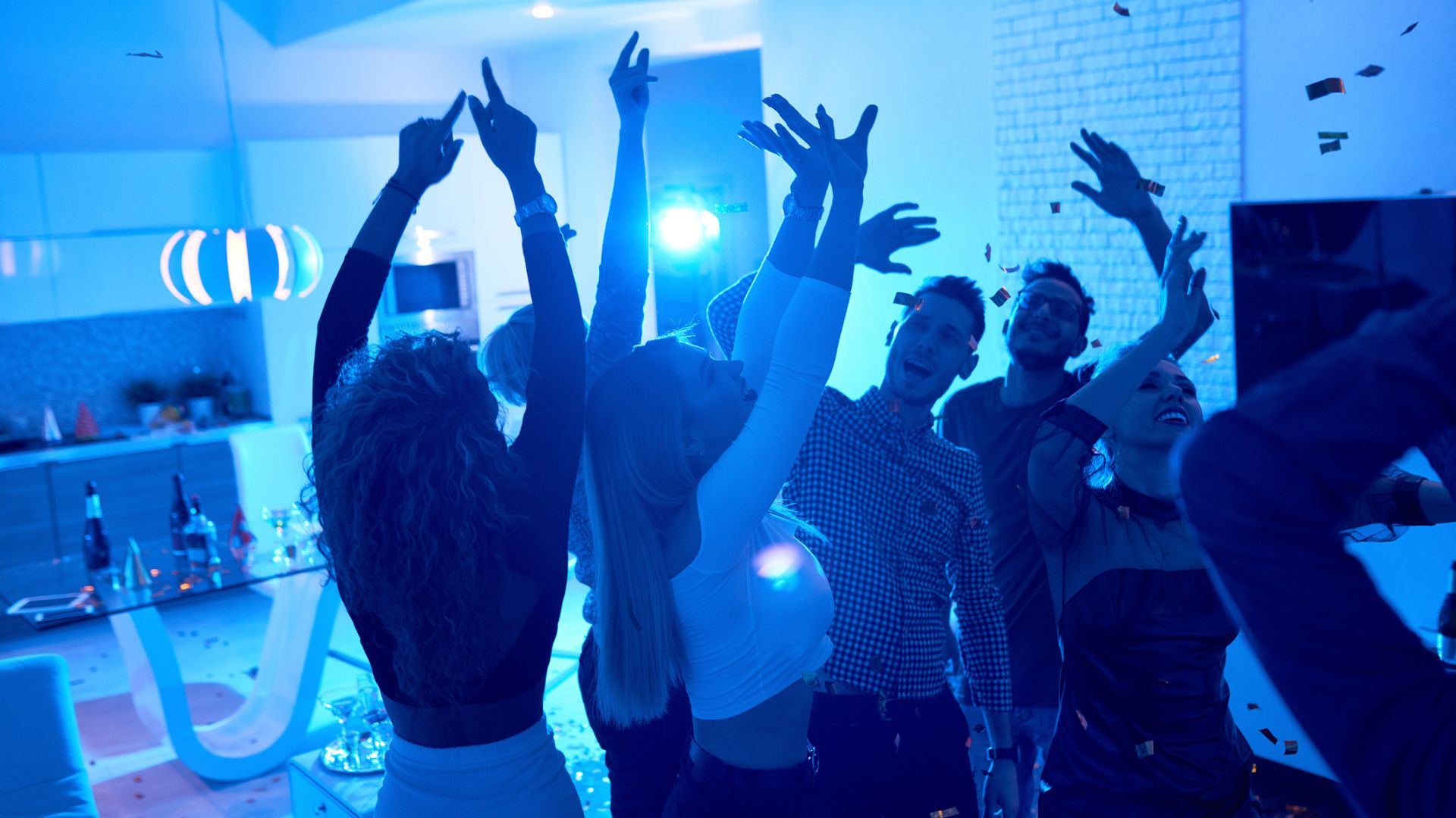 Young people under a blue light at a house party