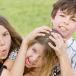 Three young siblings wrestling outdoors on the grass