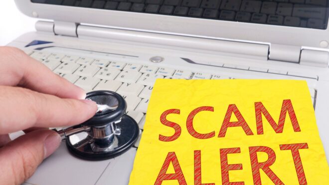 A Scam alert sign on a laptop with a stethoscope