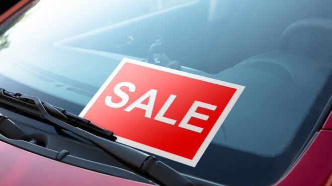 A close up of a for sale sign on a red vehicle