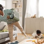 A mom trying to clean up her messy living room with a toddler playing nearby