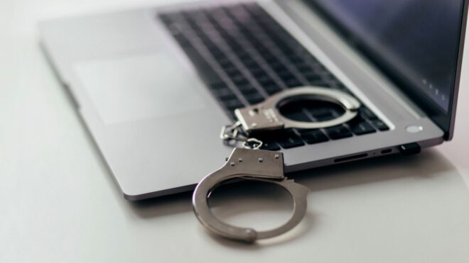 A photo of an opened laptop with handcuffs nearby