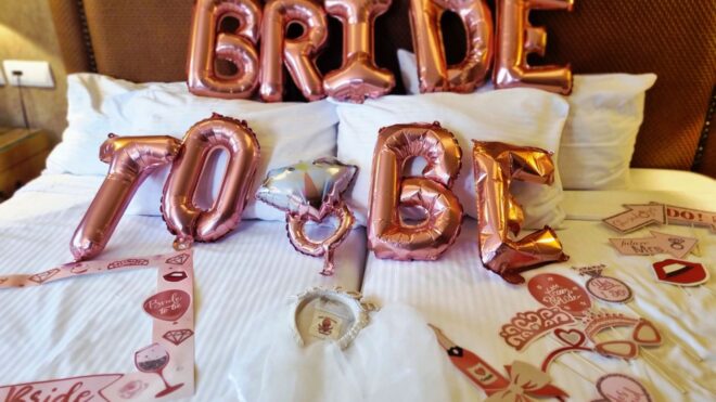 A photo of rose gold ‘Bride to be’ party decorations on a bed