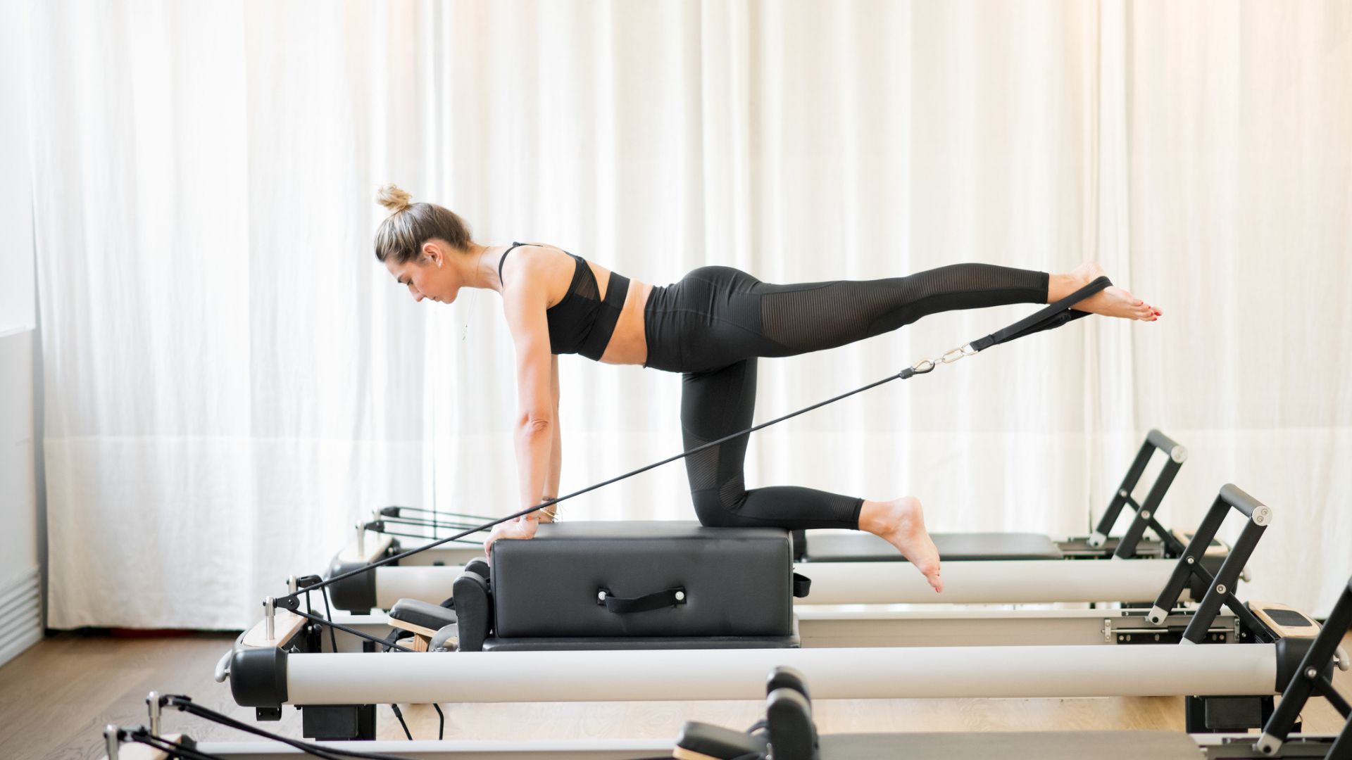 A woman in workout gear performing a Pilates diagonal stabilization pose