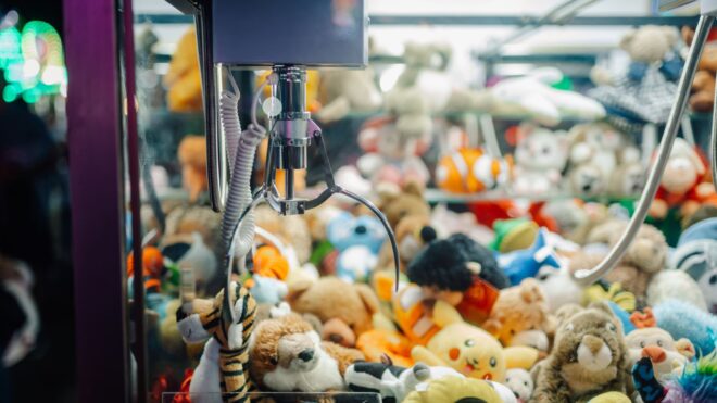 Claw crane picking up plush toys in arcade game machine