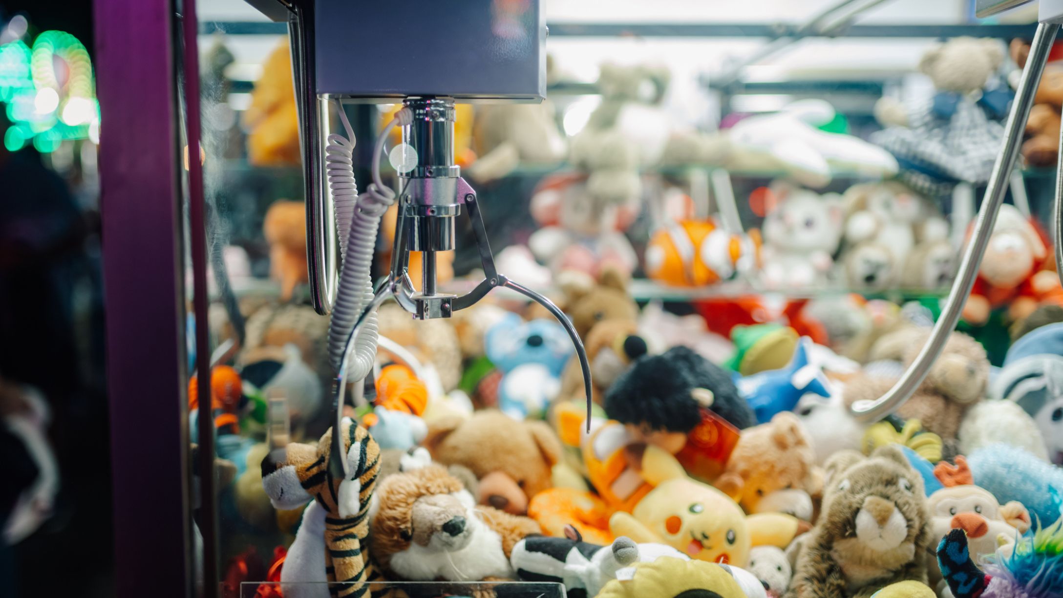 Claw crane picking up plush toys in arcade game machine