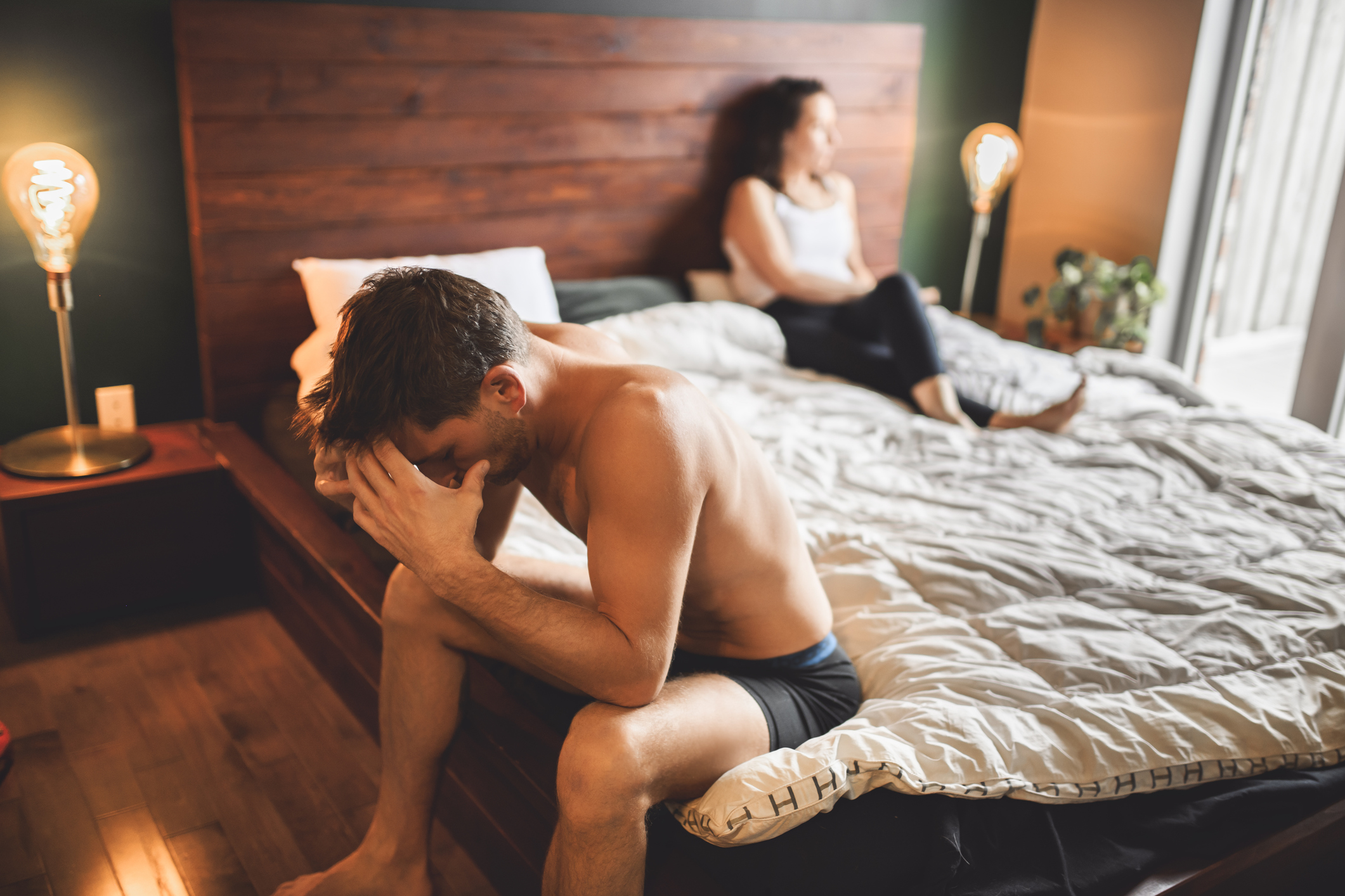 A Lover couple lies in bed, no sexual desire. Men on sit on side of the bed